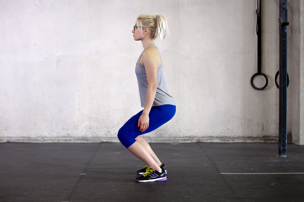 woman doing squat wrong by bending at the knees first
