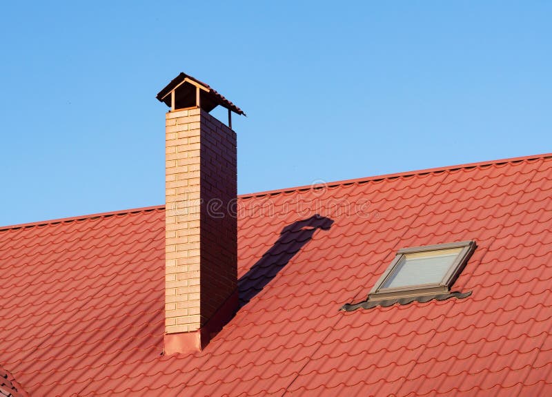 Close up of brick chimney and skylight on the metal tile roof royalty free stock photo
