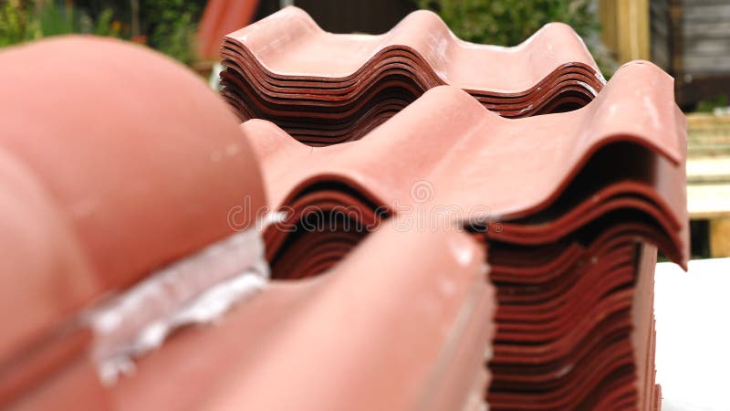 Close-up of red steel roofing panels piles lying outside and prepared for house`s roof construction. Clip. Materials and stock photography