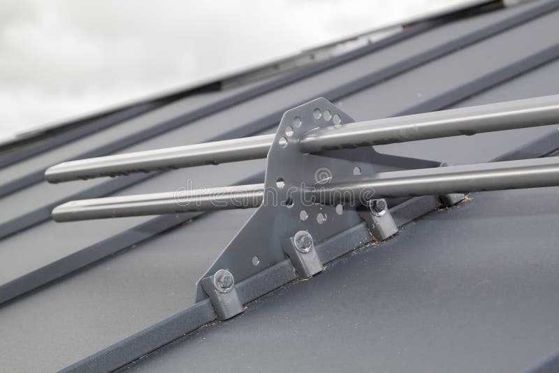 Close up view of fastening metal snow retainer with screws to the roof stock image