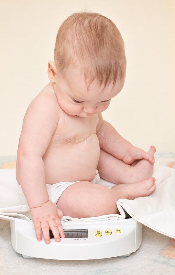 Cute baby check own weight. On home scales royalty free stock image