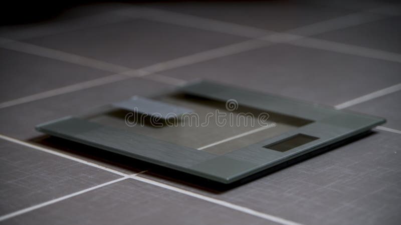 Glass modern design digital weight scales. In bathroom on tiled floor royalty free stock image