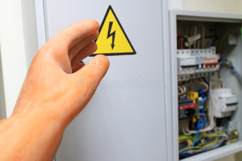 Hand in rubber insulating glove stretches to the electrical panel stock photo