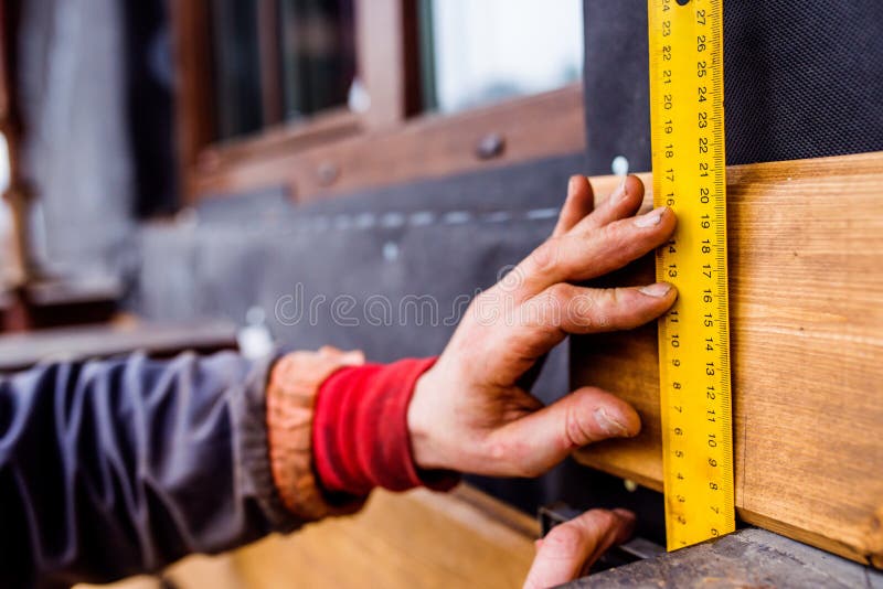 Hand of unrecognizable worker, doing facade, measuring wooden bo royalty free stock photography