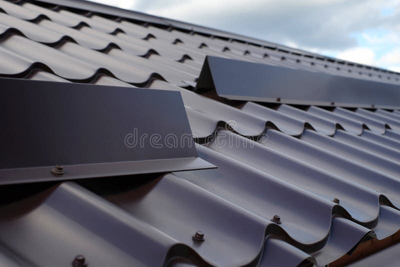 Metal tile roofing construction. Close up snow guard on the roof. stock photo