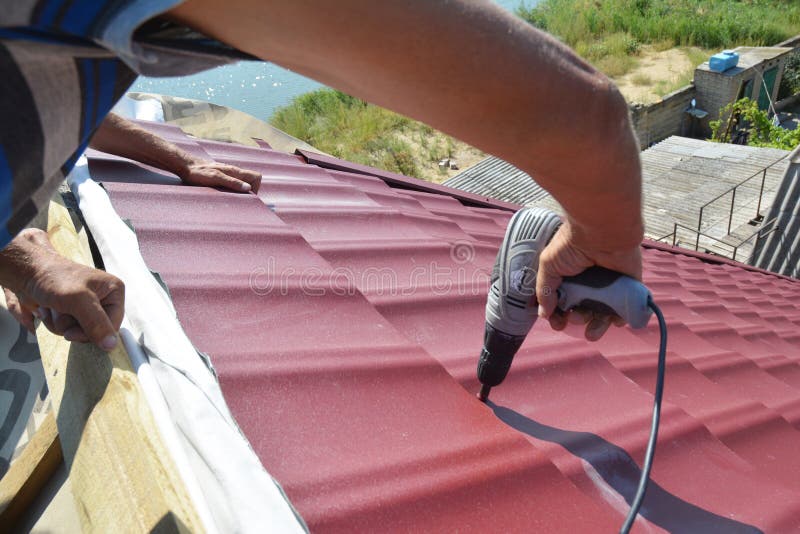 Roofing contractors installing metal roof tile for roof repair. Roofing construction royalty free stock photo