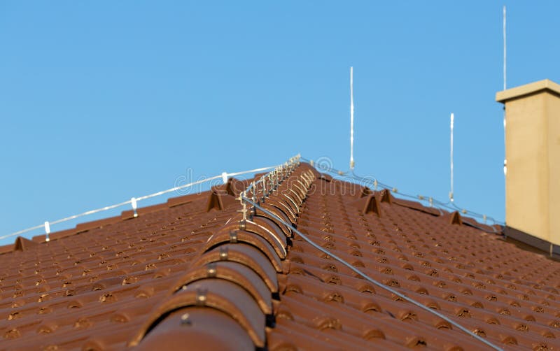 Tile roof with chimney and lightning protection system installed. Lightning rods. Close-up shot. Lightning conductor stock photo