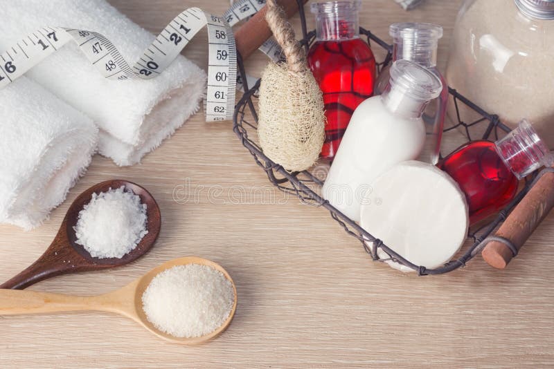 Two white towels, basket with hampoo, cream, lotion bottles, wis. P of bast, measuring tape, sand and sea salt on wood. Bath, sauna, Spa slimming, weight loss stock photo