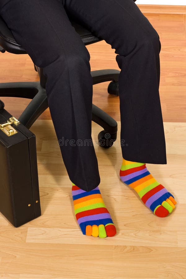 Unusual businessman. Businessman sitting in armchair and wearing unusual colorful socks stock images