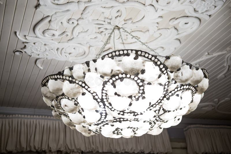 Vintage chandelier hanging under white ceiling with stucco moldings.  stock photography