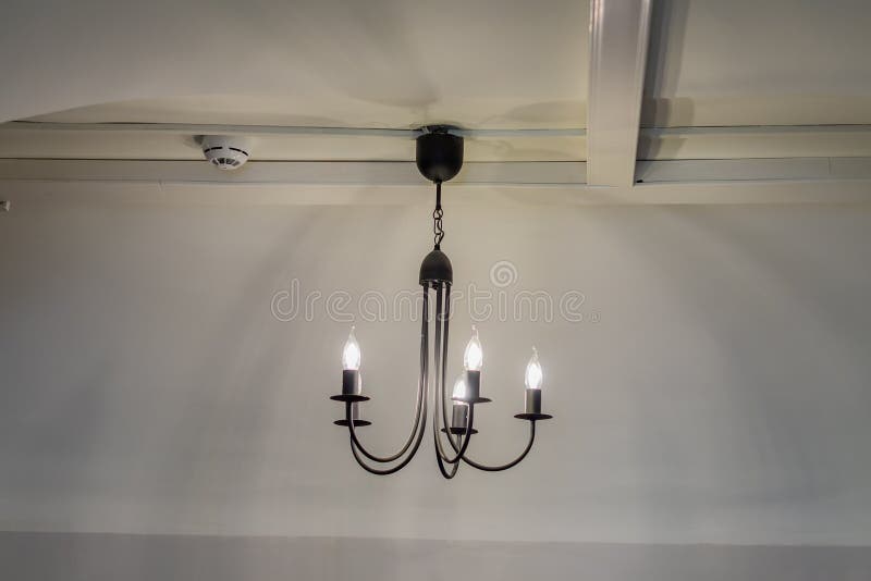 Vintage chandelier hanging under white ceiling with stucco moldings.  stock photo