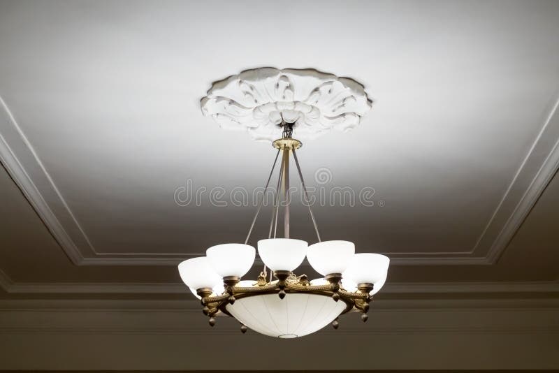 Vintage chandelier hanging under white ceiling with stucco moldings.  royalty free stock images