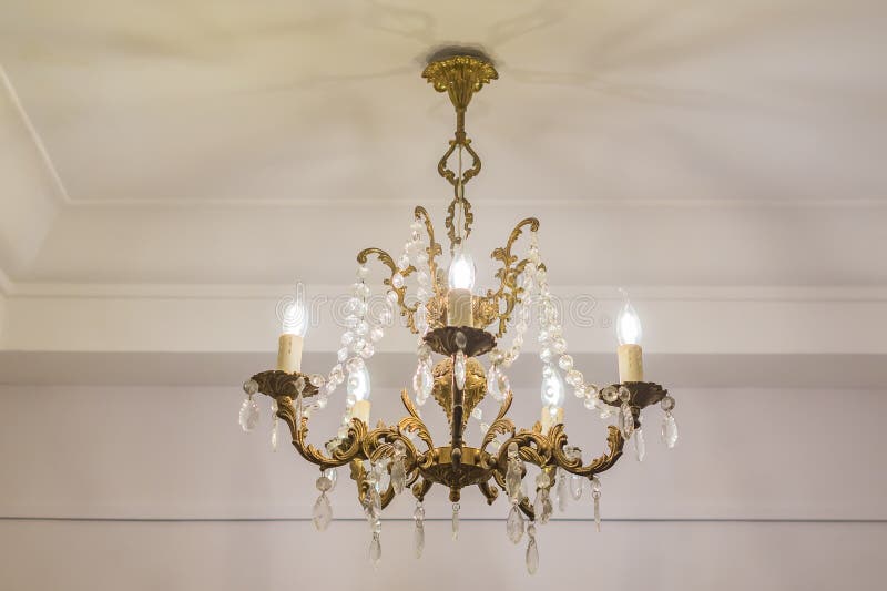 Vintage chandelier hanging under white ceiling with stucco moldings.  stock photography