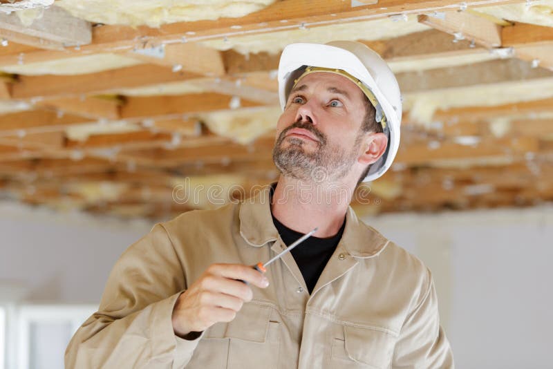 Worker working on wooden ceiling in house stock image