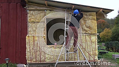 Worker with helmet insulating with rock wool wooden house wall stock video footage